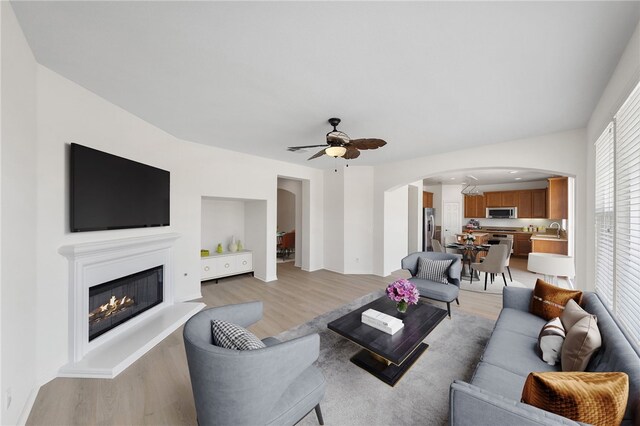 23812 Cook Ct, Wildomar, CA 92595 - living room featuring arched walkways, light wood-type flooring, a ceiling fan, and a glass covered fireplace