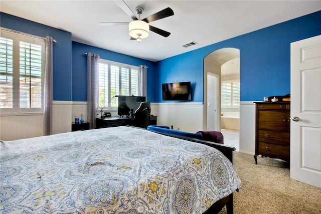 44837 Checkerbloom Dr, Temecula, CA 92592 - bedroom featuring a wainscoted wall, arched walkways, carpet flooring, a ceiling fan, and ensuite bath
