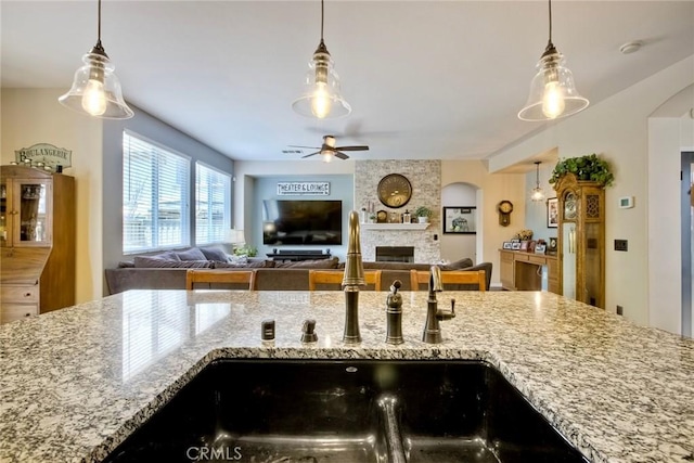 44837 Checkerbloom Dr, Temecula, CA 92592 - kitchen with ceiling fan, light stone counters, a fireplace, and hanging light fixtures