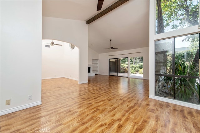 9411 Friendly Woods Ln, Whittier, CA 90605 - unfurnished living room featuring a ceiling fan, high vaulted ceiling, a fireplace with raised hearth, beamed ceiling, and plenty of natural light
