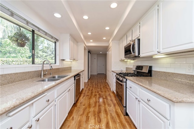 9411 Friendly Woods Ln, Whittier, CA 90605 - kitchen with appliances with stainless steel finishes, recessed lighting, white cabinets, light wood-type flooring, and decorative backsplash