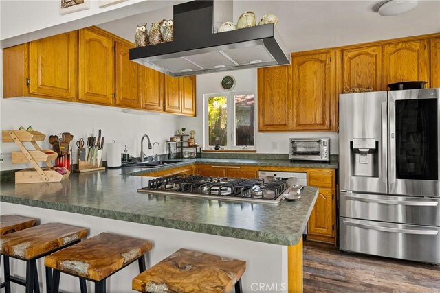 2023 Republic Ave, Costa Mesa, CA 92627 - kitchen featuring appliances with stainless steel finishes, wall chimney range hood, a peninsula, brown cabinetry, and dark countertops