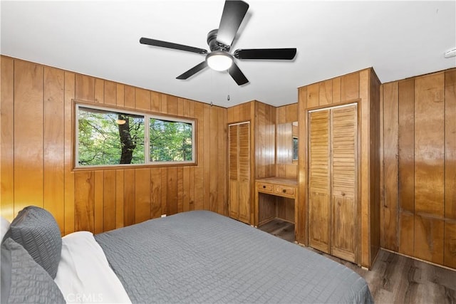 990 Nesthorn Dr, Crestline, CA 92325 - bedroom with wood finished floors, wooden walls, a ceiling fan, and two closets