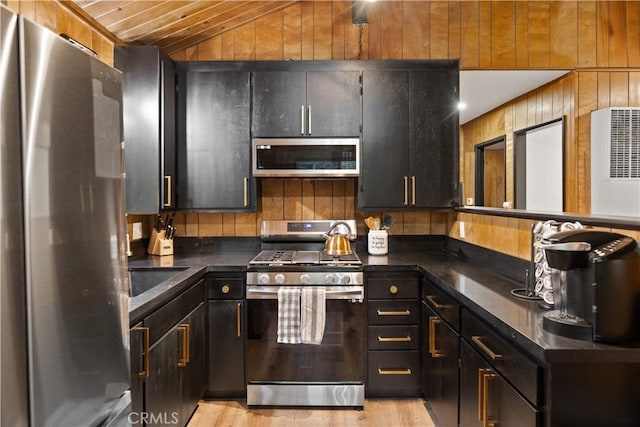 990 Nesthorn Dr, Crestline, CA 92325 - kitchen featuring appliances with stainless steel finishes, dark countertops, vaulted ceiling, light wood-style floors, and wood walls