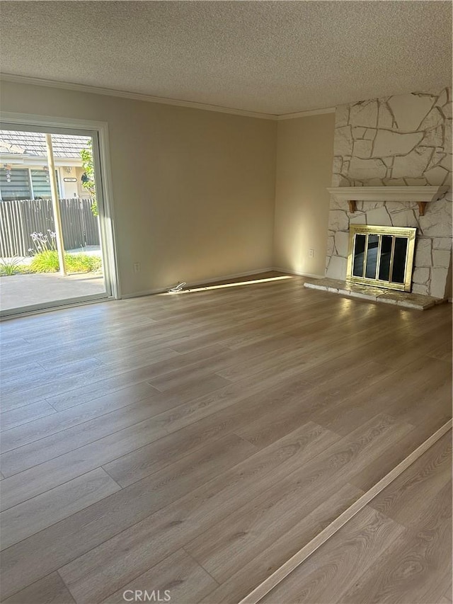 22943 Maple Ave Unit A, Torrance, CA 90505 - unfurnished living room featuring a textured ceiling, ornamental molding, wood finished floors, and a stone fireplace