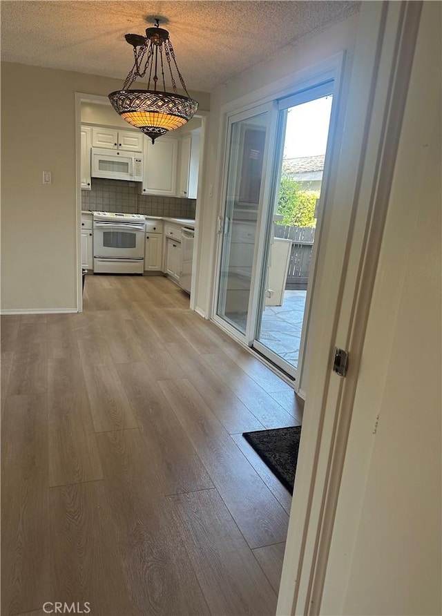 22943 Maple Ave Unit A, Torrance, CA 90505 - kitchen featuring white appliances, light wood-style floors, white cabinets, tasteful backsplash, and a textured ceiling
