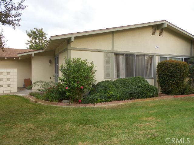 704 Avenida Sevilla Unit D, Laguna Woods, CA 92637 - view of side of property with stucco siding, a yard, and an attached garage