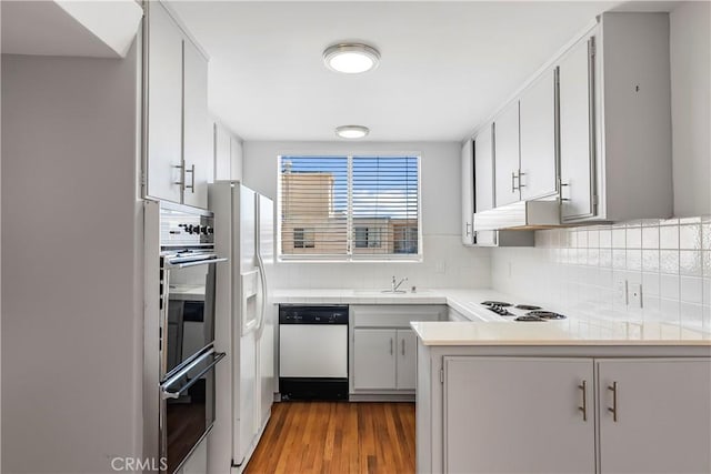 5429 Newcastle Ave Unit 309, Encino, CA 91316 - kitchen featuring white appliances, decorative backsplash, a peninsula, and light wood-style flooring