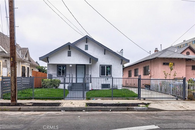 123 W 56th St, Los Angeles, CA 90037 - bungalow-style home featuring covered porch, stucco siding, a fenced front yard, and a gate