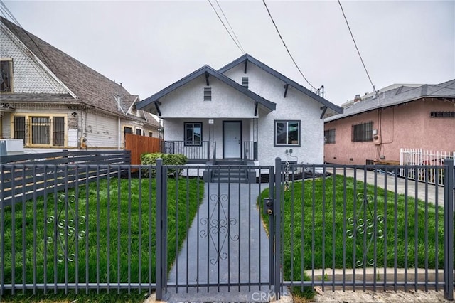 123 W 56th St, Los Angeles, CA 90037 - bungalow with a fenced front yard, covered porch, stucco siding, and a gate