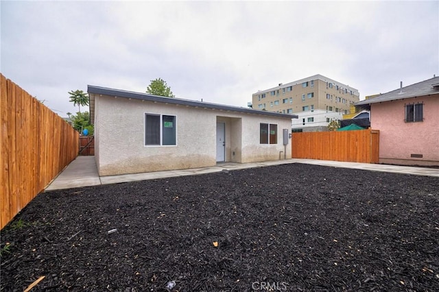 123 W 56th St, Los Angeles, CA 90037 - back of house featuring a fenced backyard, stucco siding, and a patio area