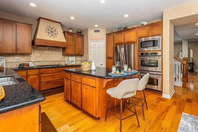 5146 Delaney Ct, Carlsbad, CA 92008 - kitchen with stainless steel appliances, custom range hood, brown cabinetry, a kitchen breakfast bar, and recessed lighting