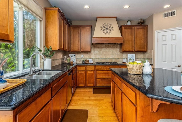 5146 Delaney Ct, Carlsbad, CA 92008 - kitchen with custom range hood, light wood-style flooring, stainless steel gas stovetop, tasteful backsplash, and dark stone counters