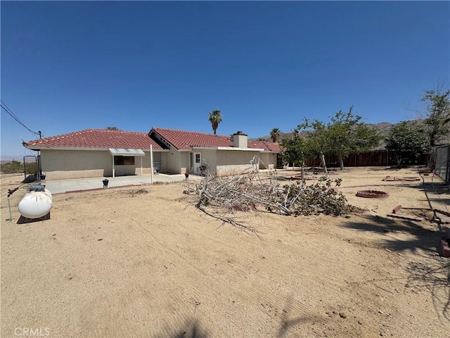 6774 Galleta Ave Unit 29, Palms, CA 92277 - back of house with a tile roof, stucco siding, a patio area, and a chimney