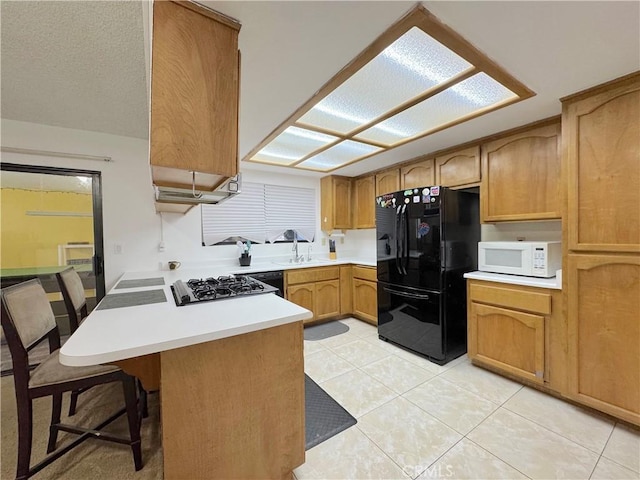 6774 Galleta Ave Unit 29, Palms, CA 92277 - kitchen featuring freestanding refrigerator, white microwave, gas stovetop, a peninsula, and light tile patterned floors