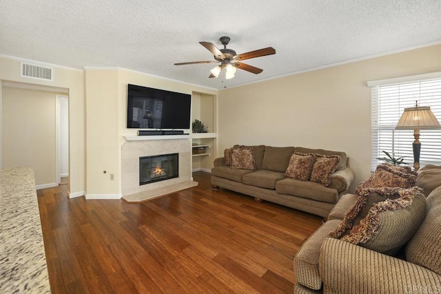 647 Boysenberry Way, Oceanside, CA 92057 - living room featuring ceiling fan, dark wood-style flooring, crown molding, a textured ceiling, and a fireplace