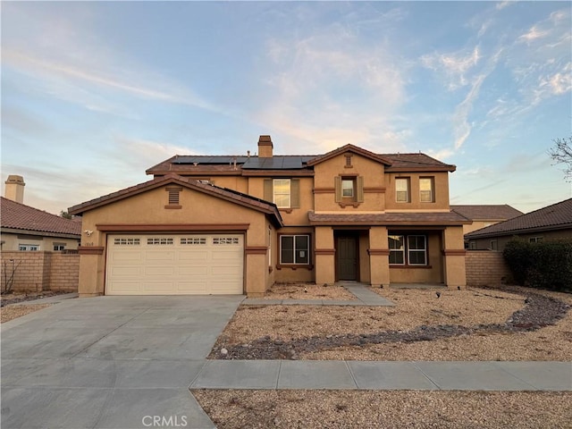 1060 Saltbush Ln, Hemet, CA 92545 - view of front of house featuring driveway, solar panels, stucco siding, an attached garage, and a chimney
