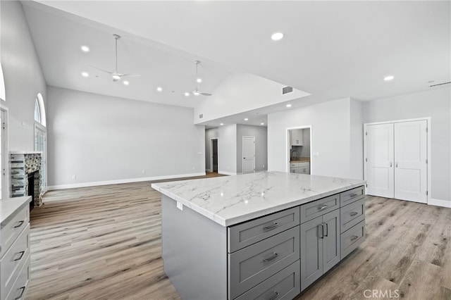 11128 Stamy Rd, Whittier, CA 90604 - kitchen with gray cabinetry, a ceiling fan, light wood-type flooring, a kitchen island, and light stone countertops