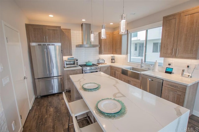 7570 Gibraltar St Unit 101, Carlsbad, CA 92009 - kitchen with stainless steel appliances, wall chimney exhaust hood, light stone countertops, brown cabinetry, and recessed lighting