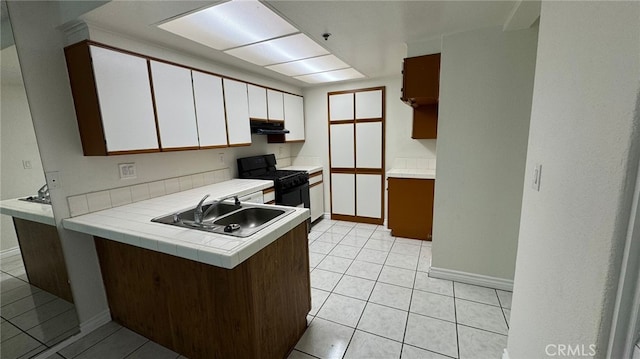 44460 15th St E Unit 13, Lancaster, CA 93535 - kitchen featuring black range with gas stovetop, a peninsula, white cabinetry, under cabinet range hood, and light tile patterned flooring