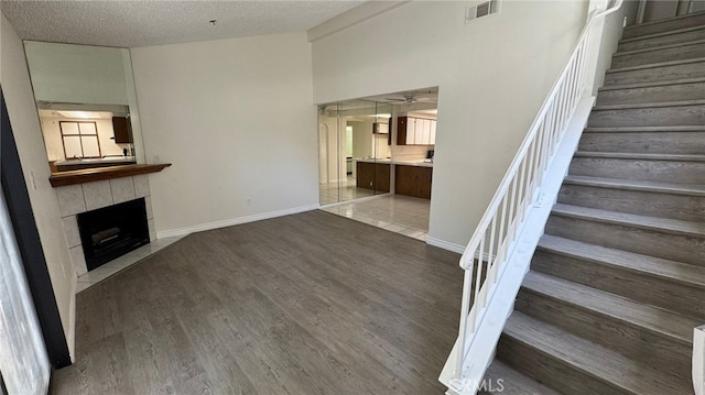 44460 15th St E Unit 13, Lancaster, CA 93535 - unfurnished living room featuring stairs, a fireplace, dark wood finished floors, a textured ceiling, and lofted ceiling