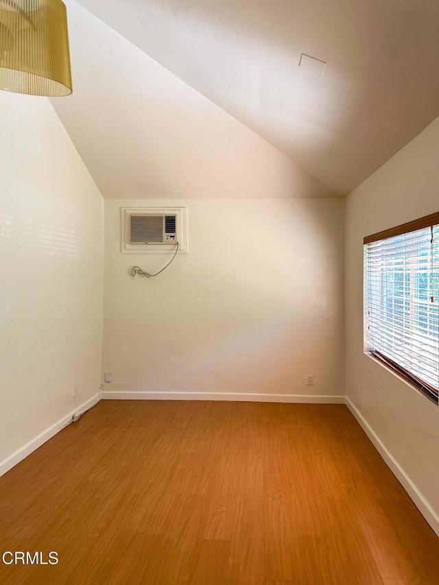 980 N Hoover St, Los Angeles, CA 90029 - empty room with a wall mounted air conditioner, lofted ceiling, and light wood finished floors