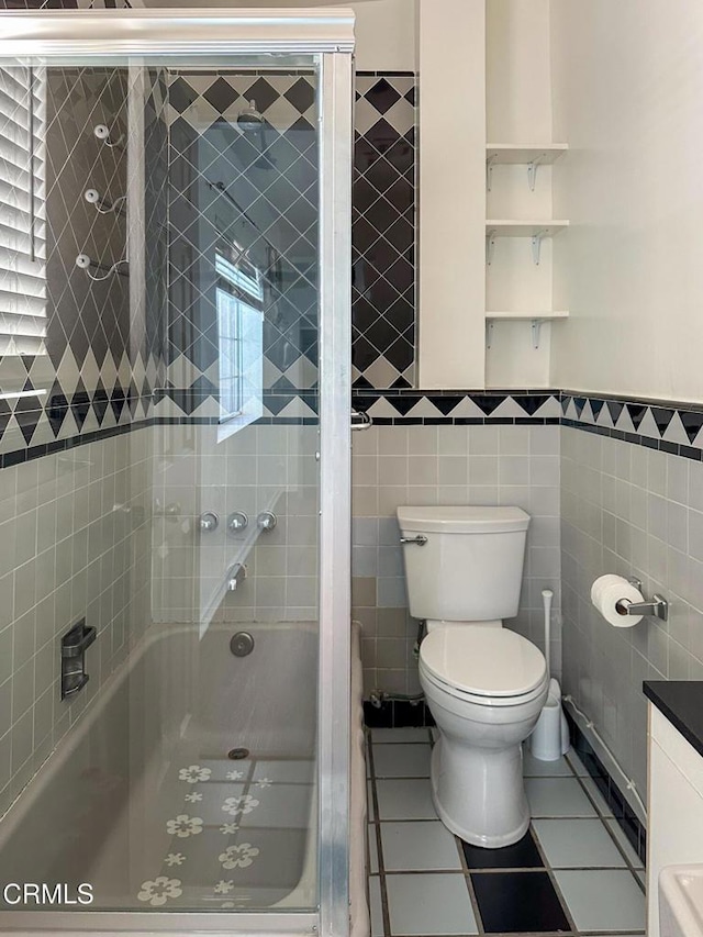 980 N Hoover St, Los Angeles, CA 90029 - full bathroom with tile walls, tile patterned floors, enclosed tub / shower combo, and wainscoting