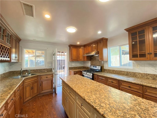 3759 Ahern Dr, Baldwin Park, CA 91706 - kitchen featuring gas stove, under cabinet range hood, dark wood-type flooring, brown cabinets, and tasteful backsplash