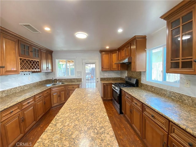 3759 Ahern Dr, Baldwin Park, CA 91706 - kitchen with stainless steel gas stove, under cabinet range hood, crown molding, dark wood finished floors, and brown cabinets