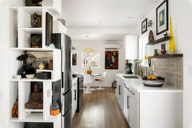 67712 Whitmore Rd Unit 29, Palms, CA 92277 - kitchen with appliances with stainless steel finishes, a wall mounted air conditioner, wood finished floors, tasteful backsplash, and open shelves
