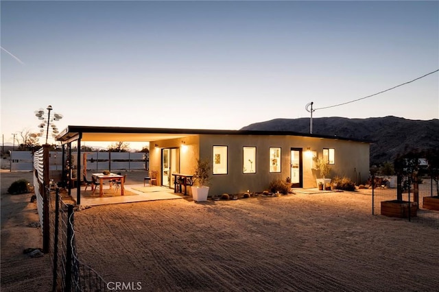 67712 Whitmore Rd Unit 29, Palms, CA 92277 - back of house at dusk featuring a mountain view and a patio