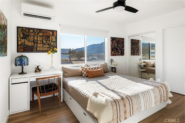 67712 Whitmore Rd Unit 29, Palms, CA 92277 - bedroom featuring a wall unit AC, a mountain view, wood finished floors, a closet, and a ceiling fan