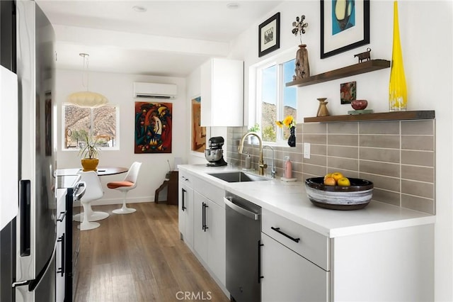 67712 Whitmore Rd Unit 29, Palms, CA 92277 - kitchen featuring appliances with stainless steel finishes, backsplash, a wall unit AC, wood finished floors, and white cabinets