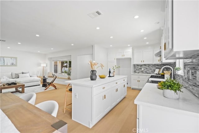 20832 Halldale Ave, Torrance, CA 90501 - kitchen with gas range oven, open floor plan, light wood-style flooring, tasteful backsplash, and white cabinets