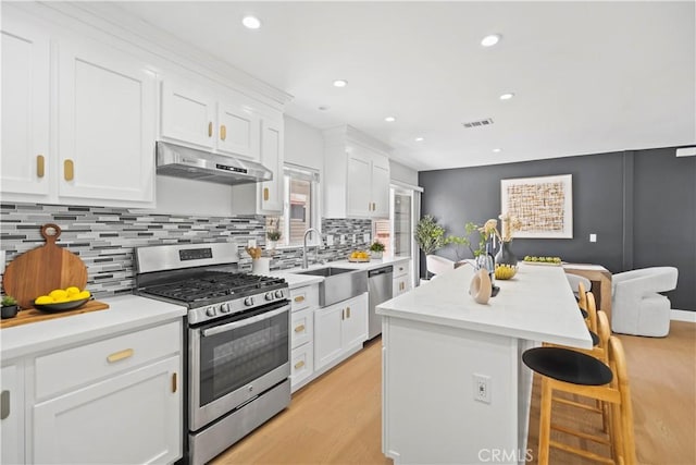 20832 Halldale Ave, Torrance, CA 90501 - kitchen with appliances with stainless steel finishes, under cabinet range hood, a kitchen breakfast bar, light wood finished floors, and white cabinets