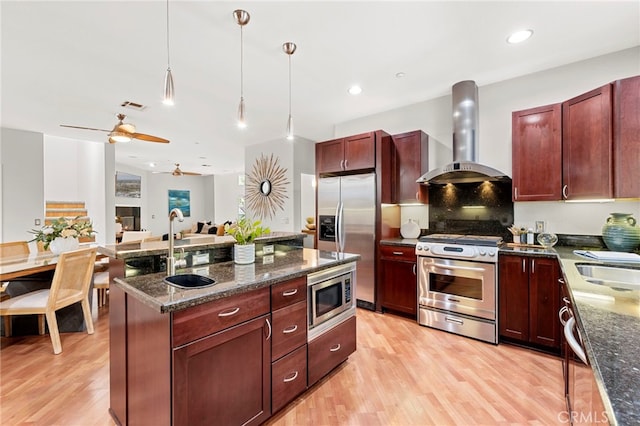 210 N Stage Coach Ln, Fallbrook, CA 92028 - kitchen featuring stainless steel appliances, wall chimney range hood, light wood finished floors, reddish brown cabinets, and recessed lighting