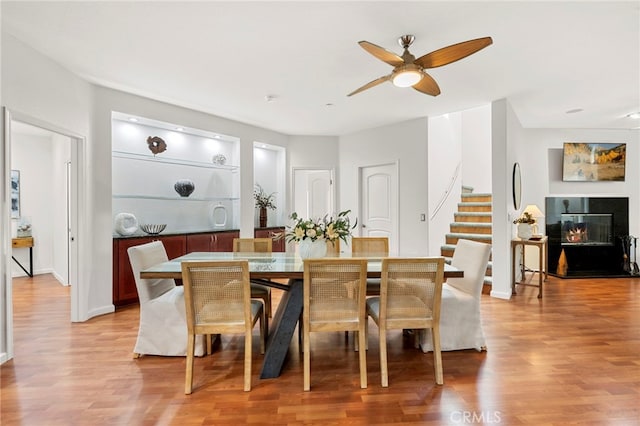 210 N Stage Coach Ln, Fallbrook, CA 92028 - dining space featuring a ceiling fan, light wood-style flooring, stairs, and a glass covered fireplace