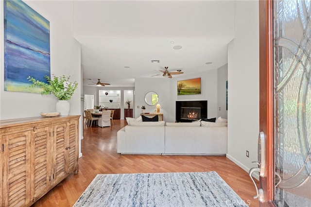 210 N Stage Coach Ln, Fallbrook, CA 92028 - living room featuring a ceiling fan, light wood-type flooring, and a lit fireplace