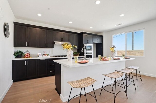 38840 Malva Rosa Dr, Palmdale, CA 93551 - kitchen with appliances with stainless steel finishes, an island with sink, light countertops, recessed lighting, and a kitchen breakfast bar