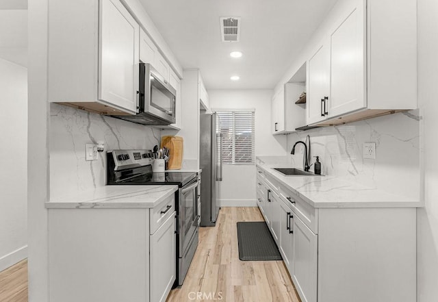 1745 Neil Armstrong Ave Unit 104, Montebello, CA 90640 - kitchen with appliances with stainless steel finishes, light wood-style flooring, open shelves, white cabinets, and recessed lighting