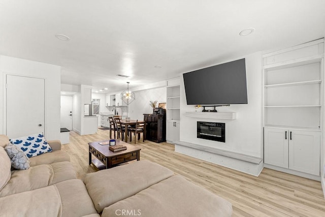 1745 Neil Armstrong Ave Unit 104, Montebello, CA 90640 - living area featuring light wood-type flooring, built in features, a glass covered fireplace, recessed lighting, and a chandelier