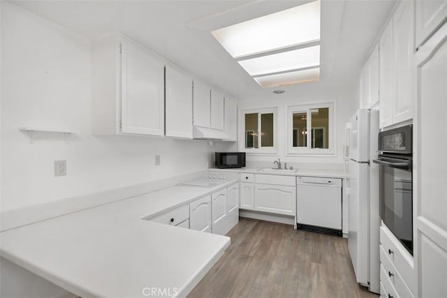 905 Ronda Sevilla Unit 0, Laguna Woods, CA 92637 - kitchen with black appliances, white cabinets, a peninsula, light countertops, and wood finished floors