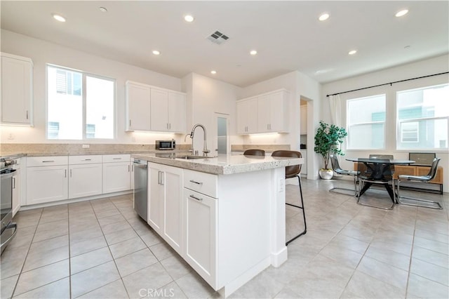 251 Sash, Irvine, CA 92618 - kitchen with light stone counters, a center island with sink, white cabinetry, light tile patterned floors, and stainless steel appliances