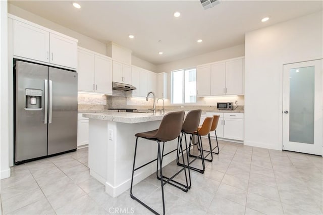 251 Sash, Irvine, CA 92618 - kitchen featuring stainless steel fridge, under cabinet range hood, white cabinets, a center island with sink, and a kitchen bar