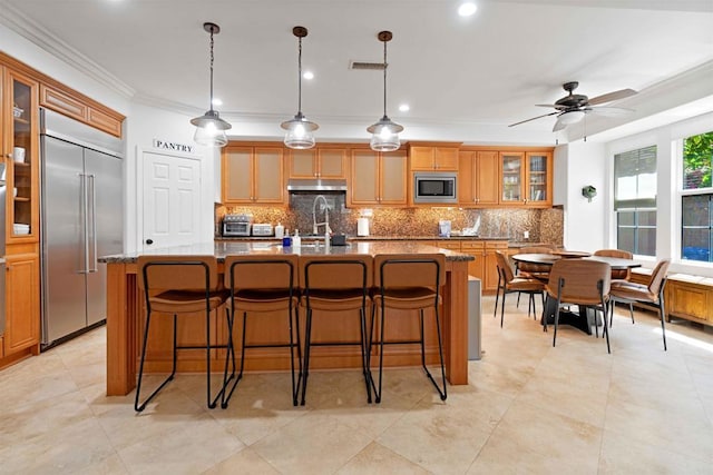 2814 Rambling Vista Rd, Chula Vista, CA 91915 - kitchen featuring built in appliances, ornamental molding, a kitchen island with sink, tasteful backsplash, and under cabinet range hood