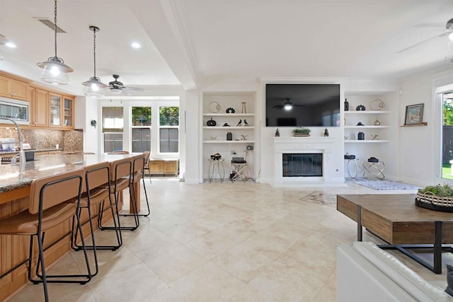 2814 Rambling Vista Rd, Chula Vista, CA 91915 - living room featuring a ceiling fan, built in shelves, crown molding, a glass covered fireplace, and light tile patterned floors