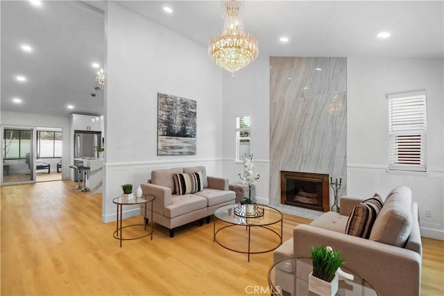 17824 Holmes Ave, Cerritos, CA 90703 - living area featuring light wood-style flooring, wainscoting, a chandelier, plenty of natural light, and a high end fireplace