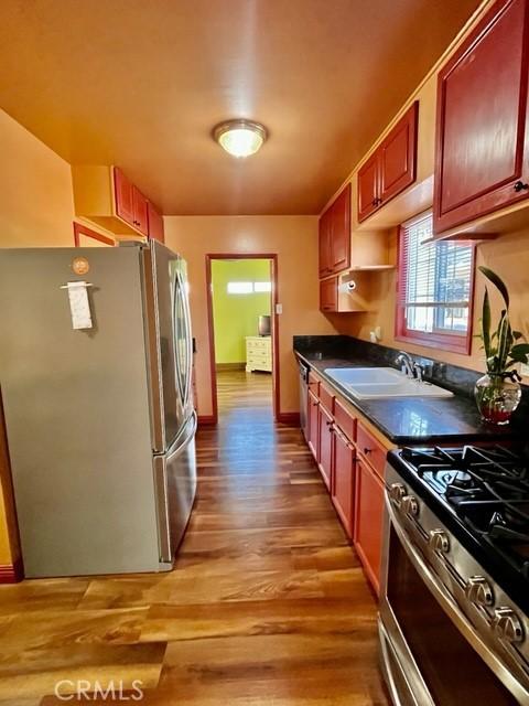 430 W 19th St, San Pedro, CA 90731 - kitchen with appliances with stainless steel finishes, dark countertops, light wood finished floors, and dark brown cabinets