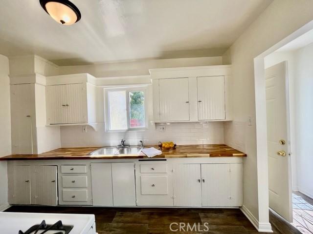 430 W 19th St, San Pedro, CA 90731 - kitchen featuring tasteful backsplash, dark wood-type flooring, white cabinets, butcher block countertops, and stove
