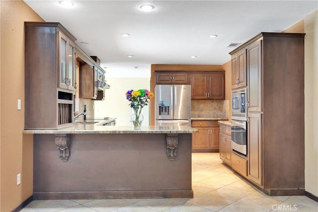 19996 Eyota Rd, Apple Valley, CA 92308 - kitchen with stainless steel appliances, light stone countertops, a peninsula, a kitchen breakfast bar, and tasteful backsplash